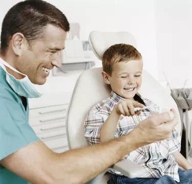 Dentist Showing a Young Boy How to Brush His Teeth With a Plaster Cast of Human Teeth