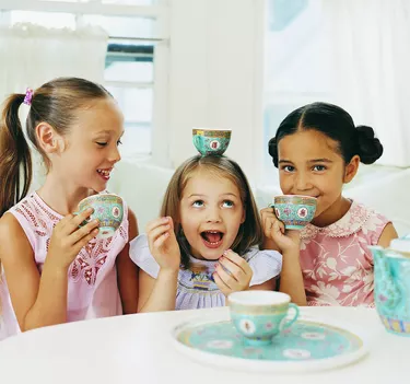 Three Girls Sitting Side by Side Having a Tea Party And Making Fun