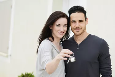 happy young couple welcome in new house showing door keys