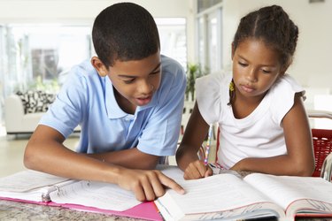 Two Children Doing Homework Together In Kitchen