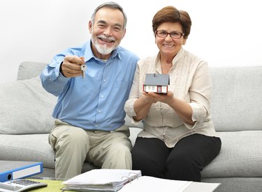 Happy senior couple holding a small house