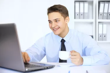 Young smiling businessman with cup of coffee in office
