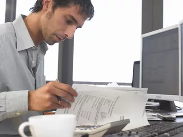 Businessman using PCs and looking at documents, close up, side view