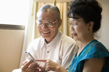 Senior couple holding mobile phone, smiling