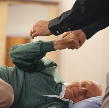Senior man lying down having physiotherapy, focus on arm
