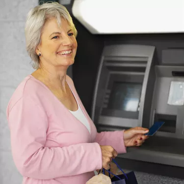 Close-up of senior woman inserting bank card into atm machine