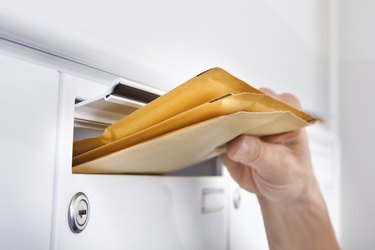 Postman Putting Letters In Mailbox