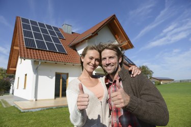 Portrait of couple giving thumbs up outside new home