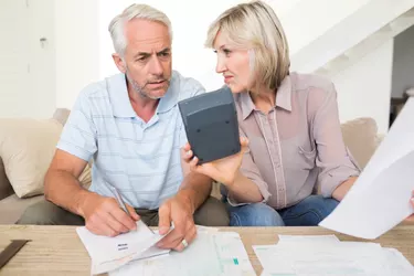 Concentrated mature couple with bills and calculator at home