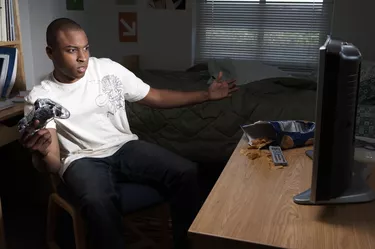 Young man playing video game in dorm room, close-up