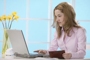 Woman using laptop with checkbook