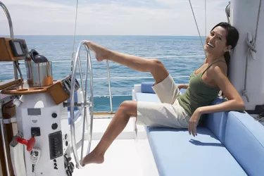 Asian woman steering sailboat with feet