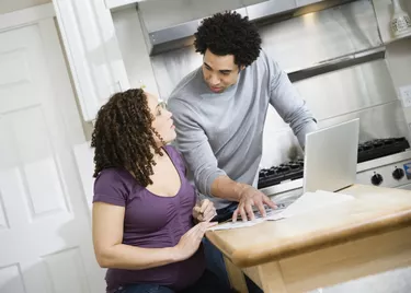 Pregnant African couple paying bills