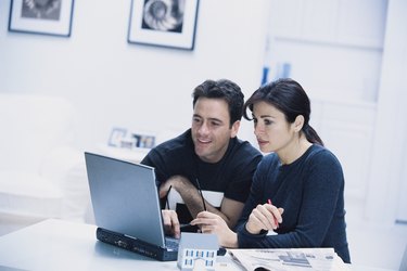 Couple with model house and laptop