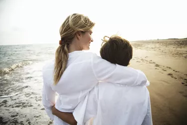 Mother and son (8-10) walking on beach, rear view, close-up