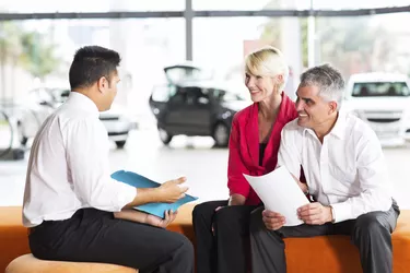 vehicle salesman explaining contract to senior couple