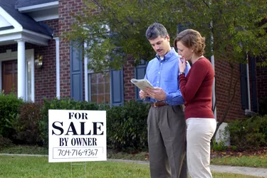 Couple reading real estate listings in front yard