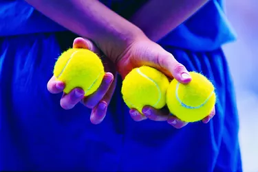 Person holding tennis balls behind back