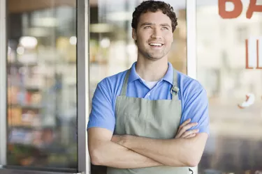 Shopkeeper smiling by storefront