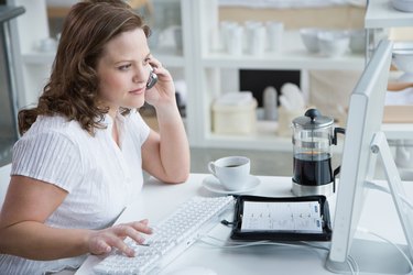 Woman sitting at desk with computer and cell phone