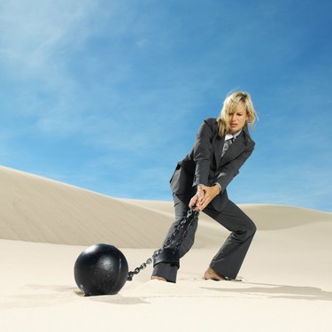 businesswoman wearing ball and chain in desert, low angle view
