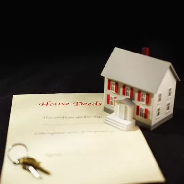 Close-up of house deeds and keys with model house beside it