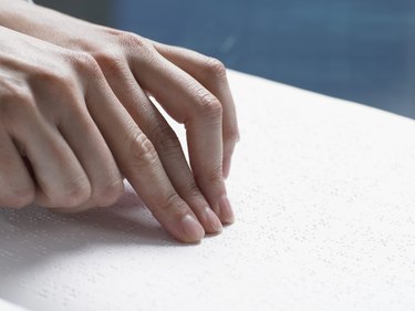 Close Up of a Hand Touching a Braille Book