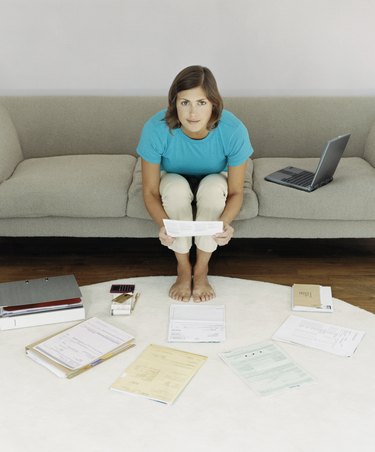 Elevated View of a Woman Sitting on a Sofa Surrounded by Bills