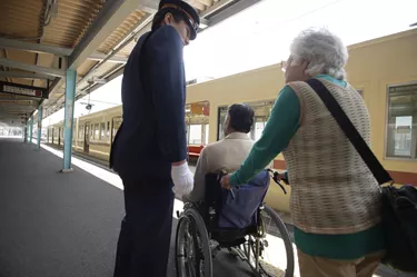Conductor and senior couple at platform, senior man in wheelchair