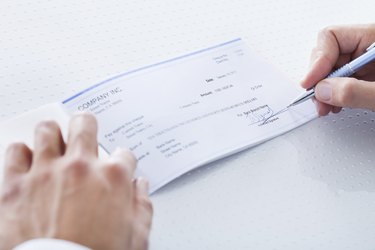 Close-up Of Hand Filling Cheque