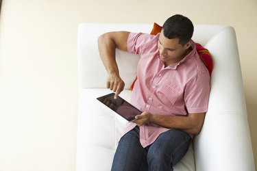 Overhead View Of Man Relaxing On Sofa Using Digital Tablet