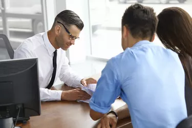 Couple Signing Salesman Contract. Car Showroom