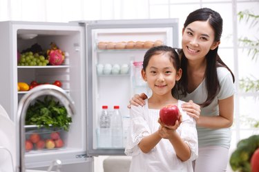 Mother and daughter holding apple in kitchen