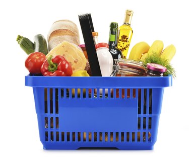 Shopping basket with variety of grocery products isolated on white