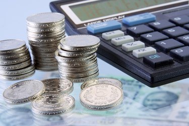 Stack of Five Rupees coins beside a calculator