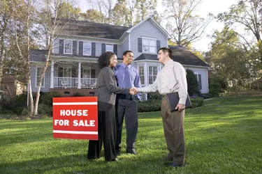 A real estate agent shakes hands with a woman as the couple has decided to purchase a suburban home