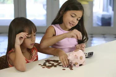 Two sisters counting coins from a piggy bank
