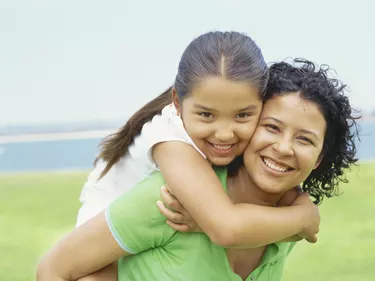 portrait of a daughter riding piggyback on her mother