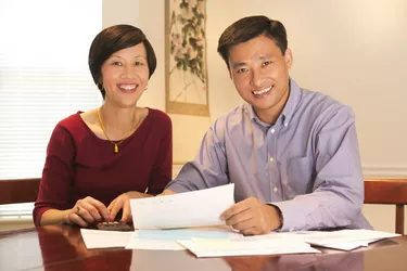 Portrait of a couple smiling at the viewer while sitting at the table going over their finances and bills
