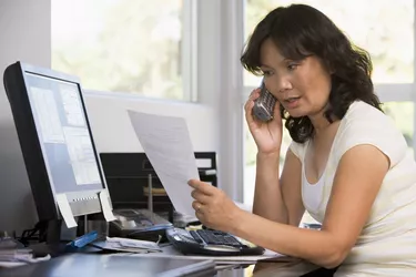 Woman in home office with paperwork using telephone