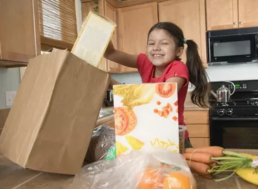Hispanic girl unpacking groceries in kitchen