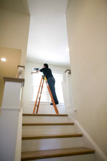 Man on ladder, fixing windows in home