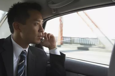 Asian businessman using cell phone in backseat of car