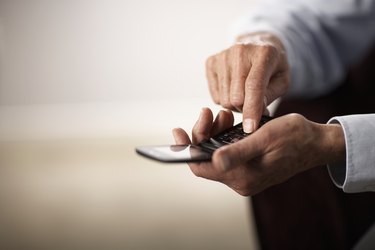 Senior man using mobile phone, close-up of hands