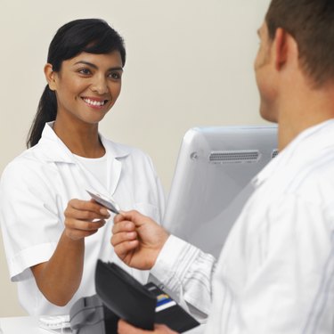 Close-up of patient paying dental nurse with credit card