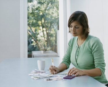 Woman Sits a Table Using a Calculator