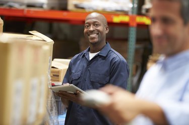 Manager In Warehouse With Worker Scanning Box