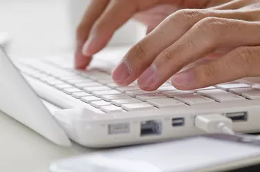 Female hands typing on white computer keyboard