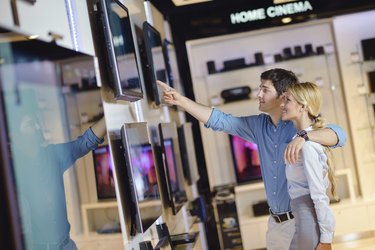 Young couple in consumer electronics store buy tv