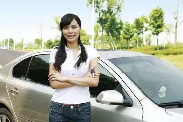 Young woman holding car keys in front of car
